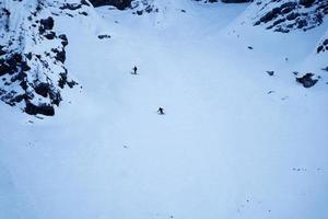 Luftdrohnenansicht von zwei Skifahrern, die im Triglav-Nationalpark den Berg hinunterfahren. Julische Alpen in Slowenien. Adrenalinsport und Winteraktivitäten. Backcountry-Skifahren oder alpines Skifahren. foto