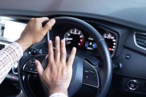 Mann, der während der Fahrt Hupe drückt, sitzt in einem Auto mit Lenkradpresse, hupt, um andere Leute zu warnen foto