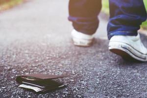 leute junge hipster hatten ledergeldbörse mit geld auf der straße verloren. Nahaufnahme der Brieftasche, die während der Reise auf dem Betonbürgersteig der Straße liegt. mit Filtertönen Retro-Vintage-Warmeffekt. foto