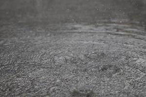 Regentropfen im Wasser schwer auf Asphalt Schatten von schwarzem Schatten und Spiegelung des dunklen Himmels in der Stadt. hoher Kontrast im Herbst foto