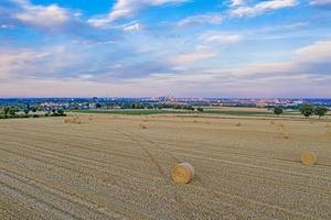 blick auf die frankfurter skyline von einem gemähten feld mit strohballen während des sonnenuntergangs foto