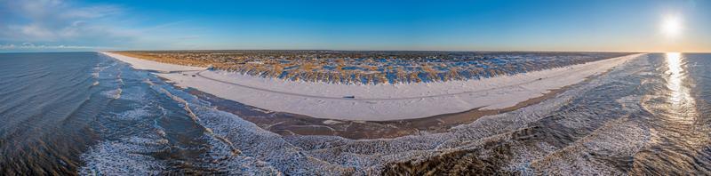 Drohnenpanorama über den Strand von Vejers in Dänemark mit Sonnenschein und Schnee foto