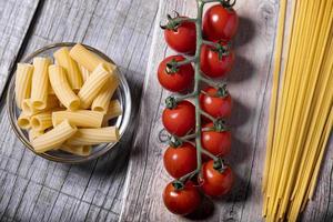 Kirschtomaten und frische Nudeln auf Holzbasis foto