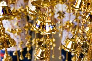 Kleine goldene Glocken wurden in einer Gruppe im thailändischen Tempel aufgehängt. foto