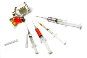Impfstoff in Plastikspritze mit medizinischen Nadeln und Fläschchen auf weißem Hintergrund. foto