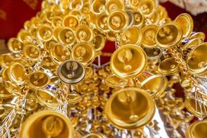 Blick nach oben Blick auf viele kleine goldene Glocken, die in einer Gruppe im thailändischen Tempel aufgehängt wurden. foto