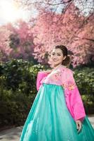 hanbok, das traditionelle koreanische kleid und das schöne asiatische mädchen mit sakura foto