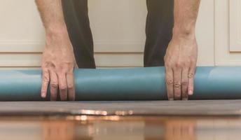 der mann benutzt seine hände, um grünes yoga zu rollen foto