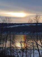 Schnee bedeckt Hügel Sonnenuntergang Regenbogenreflexion auf See foto