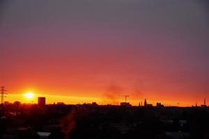 Sonnenuntergang über der Stadt mit Gebäudesilhouette foto