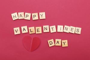 Inschrift Happy Valentine's Day mit Herzen auf rotem Hintergrund. foto