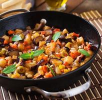 italienische caponata mit pfanne auf einem hölzernen hintergrund foto