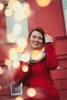 nahaufnahme lächelnde dame mit roten haaren und bokeh lichtern porträtbild foto