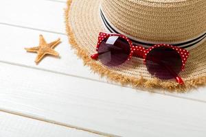 Strohhut, Sonnenbrillen und Muscheln auf weißem Holzhintergrund. draufsicht sommerferienkonzept mit kopienraum foto