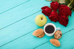 tasse kaffee mit croissants und keksen und roten rosen auf blauem holzhintergrund. Platz kopieren. Attrappe, Lehrmodell, Simulation. Ansicht von oben. Valentinstag Muttertag. foto