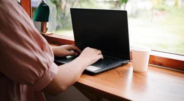 Geschäftsfrau, die an einem Laptop arbeitet, alte Dame oder Dame mittleren Alters, die ein Computerkonzept verwendet, um E-Mails zu schreiben, online zu kommunizieren, während sie an einem Tisch in einem gemütlichen Café sitzt. foto