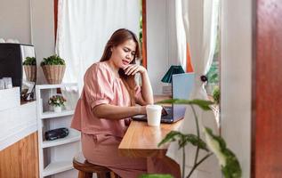 eine glückliche Frau in einem Café mit einem Laptop. Junge weiße Frau, die in einem Café sitzt und an ihrem Laptop arbeitet. foto