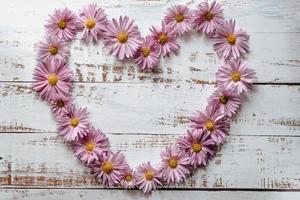 Blumen Zusammensetzung. Herzsymbol aus rosa Blüten und Blättern. Ansicht von oben, flach liegend foto