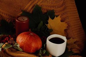 Kürbisse mit Herbstlaub in einer kuscheligen Strickdecke mit Tasse foto