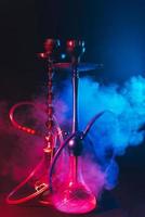 moderne shisha, shisha auf einem rauchigen schwarzen hintergrund mit neonbeleuchtung foto