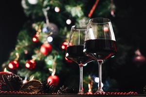 Gläser Wein auf dem Hintergrund eines geschmückten Weihnachtsbaums. Neujahr foto