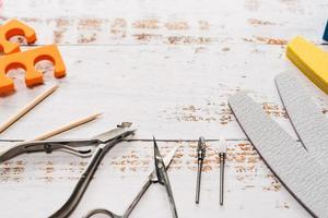 Nagelfeilen, Scheren, Zangen, Pailletten und Nagellacke auf weißem Holzhintergrund. mit Platz für Ihren Text foto