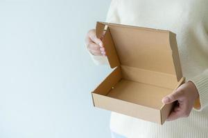 Frauenhände, die braunen Karton zum Öffnen tragen. konzept der verwendung von recyclingpapierboxen. foto