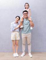 junge asiatische familie, die auf hintergrund steht foto