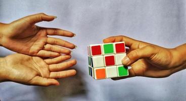 jakarta, dezember 2022. ein illustrationskonzept einer menschlichen hand, die einen rubik-würfel aufheben und damit spielen wird foto