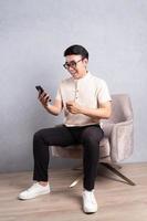 Bild eines jungen asiatischen Mannes, der auf einem Stuhl sitzt foto