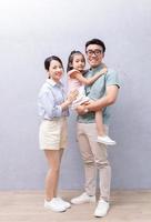 junge asiatische familie, die auf hintergrund steht foto