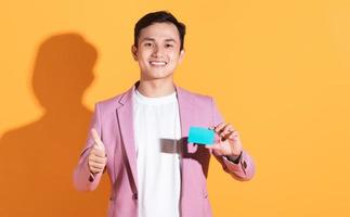 Bild eines jungen asiatischen Mannes mit Bankkarte, ATM-Karte im Hintergrund foto
