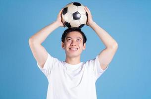 junger asiatischer mann, der ball auf hintergrund hält foto