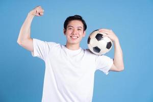 junger asiatischer mann, der ball auf hintergrund hält foto