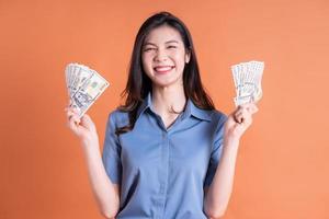 junge asiatische Geschäftsfrau, die auf orangefarbenem Hintergrund aufwirft foto