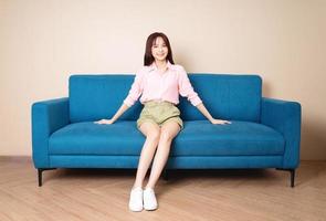 Bild einer jungen asiatischen Frau, die auf dem Sofa sitzt foto