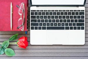 schreibtischtisch mit laptop, notizbuch, kaffeetasse, rote rose foto