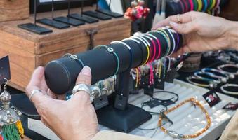 die weibliche handverkäuferin arrangierte schmuck auf dem tisch, der den verkauf an kunden auf dem lokalen markt in thailand vorbereitete. foto