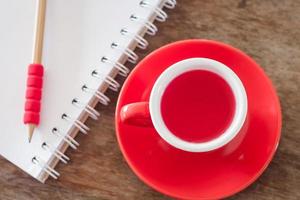 Draufsicht auf eine rote Tasse mit einem Notizbuch foto