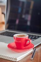 rote Kaffeetasse auf einem Laptop foto