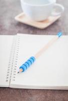 Bleistift auf einem Notizbuch mit Kaffee foto