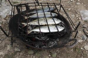 der Prozess der Herstellung von gegrilltem Fisch, der über Kokosnussschalenkohlen verbrannt wird foto