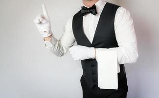 Porträt von Kellner oder Butler in schwarzer Weste und weißen Handschuhen auf weißem Hintergrund. kopierraum für die dienstleistungsbranche und professionelle gastronomie. foto