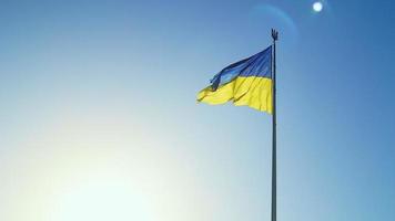Slow-Motion-Flagge der Ukraine weht im Wind vor einem wolkenlosen Himmel bei Tagesanbruch. Das ukrainische Nationalsymbol des Landes ist blau und gelb. Flaggenschlaufe mit detaillierter Stoffstruktur. foto