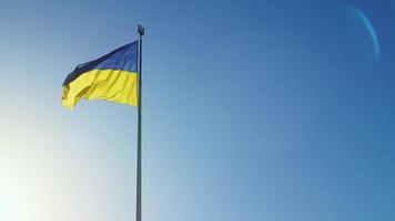 Slow-Motion-Flagge der Ukraine weht im Wind vor einem wolkenlosen Himmel bei Tagesanbruch. Das ukrainische Nationalsymbol des Landes ist blau und gelb. Flaggenschlaufe mit detaillierter Stoffstruktur.