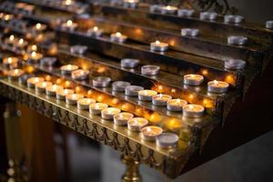 viele brennende Kerzen in der Kirche auf einem Ständer foto