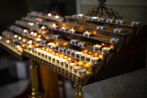 viele brennende Kerzen in der Kirche auf einem Ständer foto