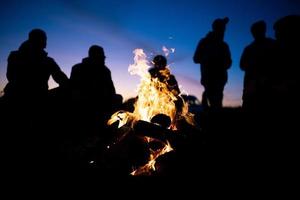 Eine Gruppe von Freunden versammelte sich nachts um das Feuer foto