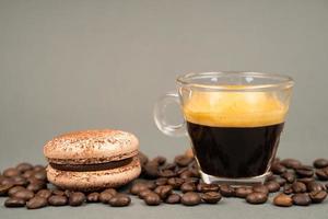 Nahaufnahme von Kaffeebecher verstreuten Kaffeebohnen und Macarons Cookies foto