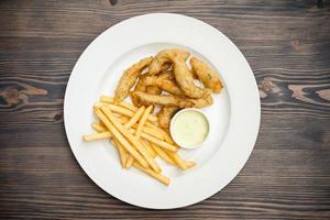 Menü mit gebratenen Garnelen und Pommes Frites mit Sauce auf einem Teller foto